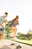 Smiling couple with skateboard in park