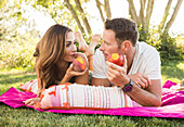Pärchen isst Pfirsiche beim Picknick im Park 