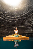 Woman sitting on wooden raft in cenote