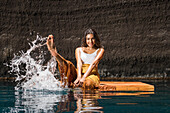Schöne Frau spritzt Wasser auf Holzfloß in Cenote
