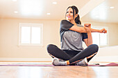 Woman sitting on floor and stretching in dance studio