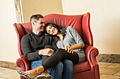 Fröhliches Paar entspannt sich gemeinsam auf einem Sessel 