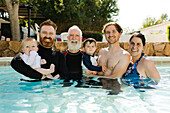 Portrait of family with boys (12-17 months, 2-3) in swimming pool
