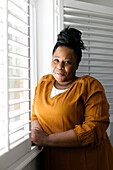 Portrait of smiling woman standing at window