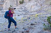 USA, New Mexico, Abiquiu, Woman with backpack photographing rocky landscape
