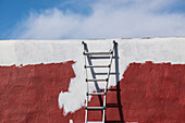 USA, New Mexico, Madrid, Ladder against partially painted brown and white wall