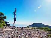 South Africa, Western Cape, Cape Town, Woman standing on cliff with arms raised