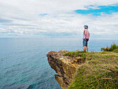 Australien, New South Wales, Port Macquarie, Frau steht auf einer Klippe und schaut auf die Aussicht
