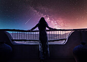 Dubai, Vereinigte Arabische Emirate, Frau in Luxusresort in der Wüste beobachtet Sternschnuppe am nächtlichen Sternenhimmel