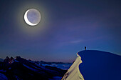Schweiz, Kanton Bern, Jungfrau, Bergsteiger auf Berggipfel beobachtet Mond am Nachthimmel
