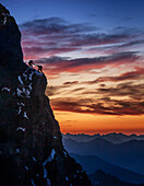 France, Haute Savoie, Chamonix, Silhouettes of climbers on rocky edge of Mont Blanc at sunset