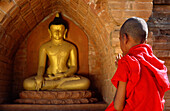 Myanmar, Mandalay, Mönchsnovize betet vor einer Buddha-Statue im Tempel