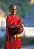 Myanmar, Mandalay, buddhistischer Mönch hält Schalen während der morgendlichen Almosengabe