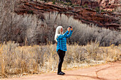 USA, Utah, Escalante, Woman taking pictures while hiking in Grand Staircase-Escalante National Monument