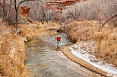 USA, Utah, Escalante, Woman wading across Escalante River in Grand Staircase-Escalante National Monument