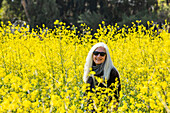 Porträt einer lächelnden älteren Frau in einem Feld mit wildem Senf
