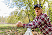 Porträt eines älteren Landwirts, der sich an einen Holzzaun in der Nähe von Sun Valley lehnt