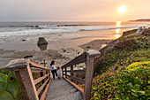 USA, California, Cayucos, Mother and daughter (4-5) on stairway to beach at sunset