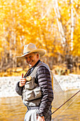 USA, Idaho, Bellevue, Porträt eines lächelnden älteren Mannes beim Fliegenfischen im Big Wood River im Herbst