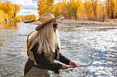 USA, Idaho, Bellevue, Senior woman fly-fishing in Big Wood River in autumn