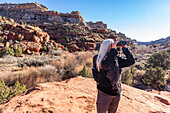 Vereinigte Staaten, Utah, Escalante, Älterer Wanderer schaut durch ein Fernglas