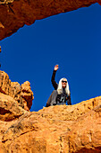 Vereinigte Staaten, Utah, Escalante, Älterer Wanderer auf Sandsteinfelsen sitzend