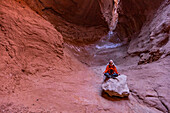 United States, Utah, Escalante, Senior female hiker sitting on rock in canyon