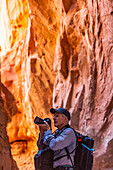 United States, Utah, Escalante, Senior hiker exploring and photographing rock formations in Kodachrome Basin State Park near Escalante Grand Staircase National Monument