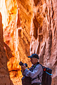Vereinigte Staaten, Utah, Escalante, Älterer Wanderer erkundet und fotografiert Felsformationen im Kodachrome Basin State Park in der Nähe des Escalante Grand Staircase National Monument