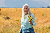USA, Idaho, Bellevue, Portrait of senior woman holding bunch of sunflowers