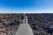 USA, Idaho, Arco, Family walking through lava field