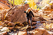 USA, Utah, Zion National Park, Ältere Wanderin beim Überqueren eines Baches