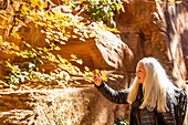Vereinigte Staaten, Utah, Zion National Park, Ältere blonde Frau schaut auf Felsen