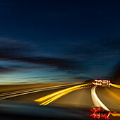 Unscharfes Bild von Lichtern auf dem Highway in der Abenddämmerung