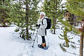 United States, Idaho, Sun Valley, Senior woman wearing snowshoes in forest