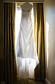 Wedding dress hanging against window