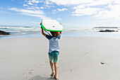South Africa, Hermanus, Boy (8-9) with surfboard on beach