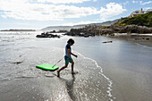 Südafrika, Hermanus, Junge (8-9) mit Surfbrett am Strand