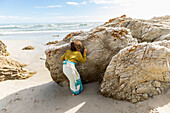 Südafrika, Hermanus, Junge (8-9) versteckt sich hinter Felsen am Strand