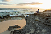 South Africa, Western Cape, Mother and daughter (16-17) sitting on beach at sunset in Lekkerwater Nature Reserve