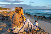 South Africa, Western Cape, Woman sitting on beach looking at ocean in Lekkerwater Nature Reserve