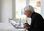 Älterer Mann arbeitet zu Hause an einem Laptop-Computer