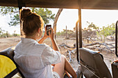 Afrika, Namibia, Mädchen (16-17) im Safarifahrzeug beim Fotografieren