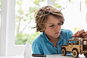 Boy (8-9) building wooden toy car at home