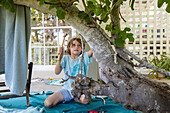 Boy (8-9) using hammer to build treehouse
