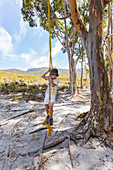 Südafrika, Stanford, Junge (8-9) spielt auf einem Baumseil im Phillipskop Naturreservat