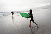 Mädchen (16-17) und Junge (8-9) beim Bodyboarden am Grotto Beach