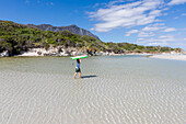 South Africa, Hermanus, Boy (8-9) carrying body board on Grotto Beach