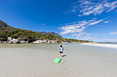 South Africa, Hermanus, Boy (8-9) pulling body board on Grotto Beach