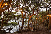 Junge (10-11) steht zwischen Bäumen an der Lagune